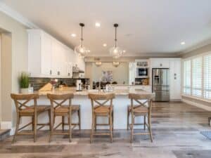 Bright kitchen with white cabinetry, granite countertops, and pendant lighting.