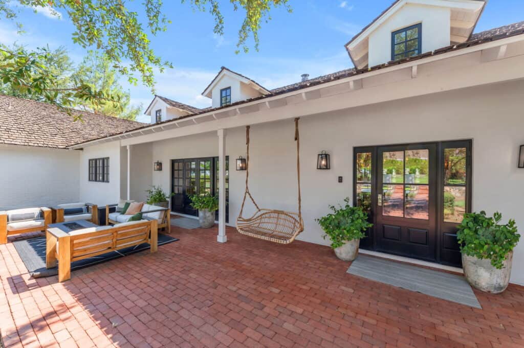 Stylish home exterior with black-framed glass doors, outdoor lighting, and lush greenery.