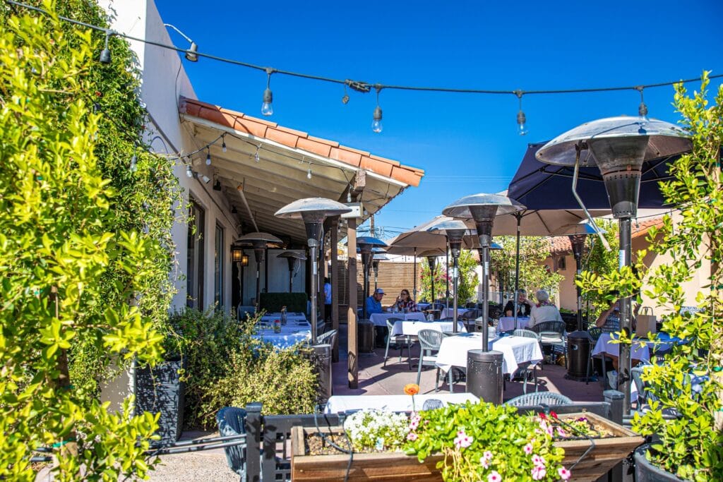 Outdoor patio dining with umbrellas and string lights at Meredith Lane restaurant.